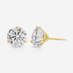 A pair of yellow gold stud earrings, one round-cut and one oval-cut, set with clear gemstones on a light gray background.
