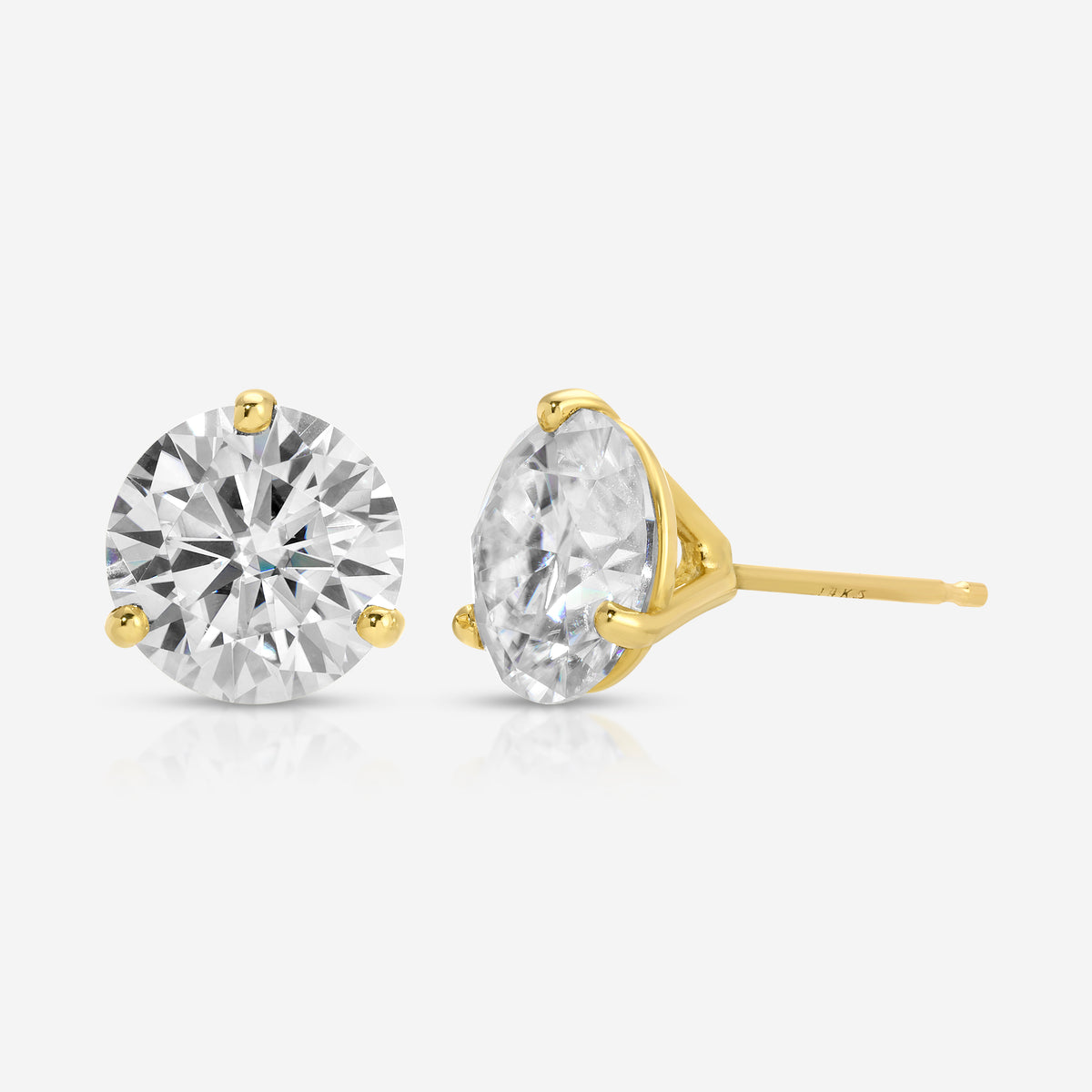 A pair of yellow gold stud earrings, one round-cut and one oval-cut, set with clear gemstones on a light gray background.