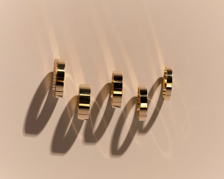 Cigar band rings in polished yellow gold displayed in a vertical arrangement, highlighting width, finish, and clean edges.