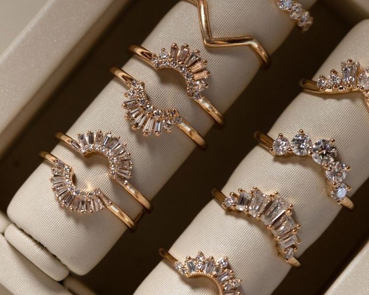 A collection of contour wedding bands in yellow gold with curved diamond settings, displayed to highlight their varied shapes and profiles.