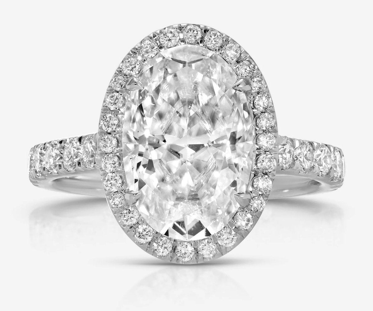 Oval halo engagement ring with pavé diamond band in white gold.