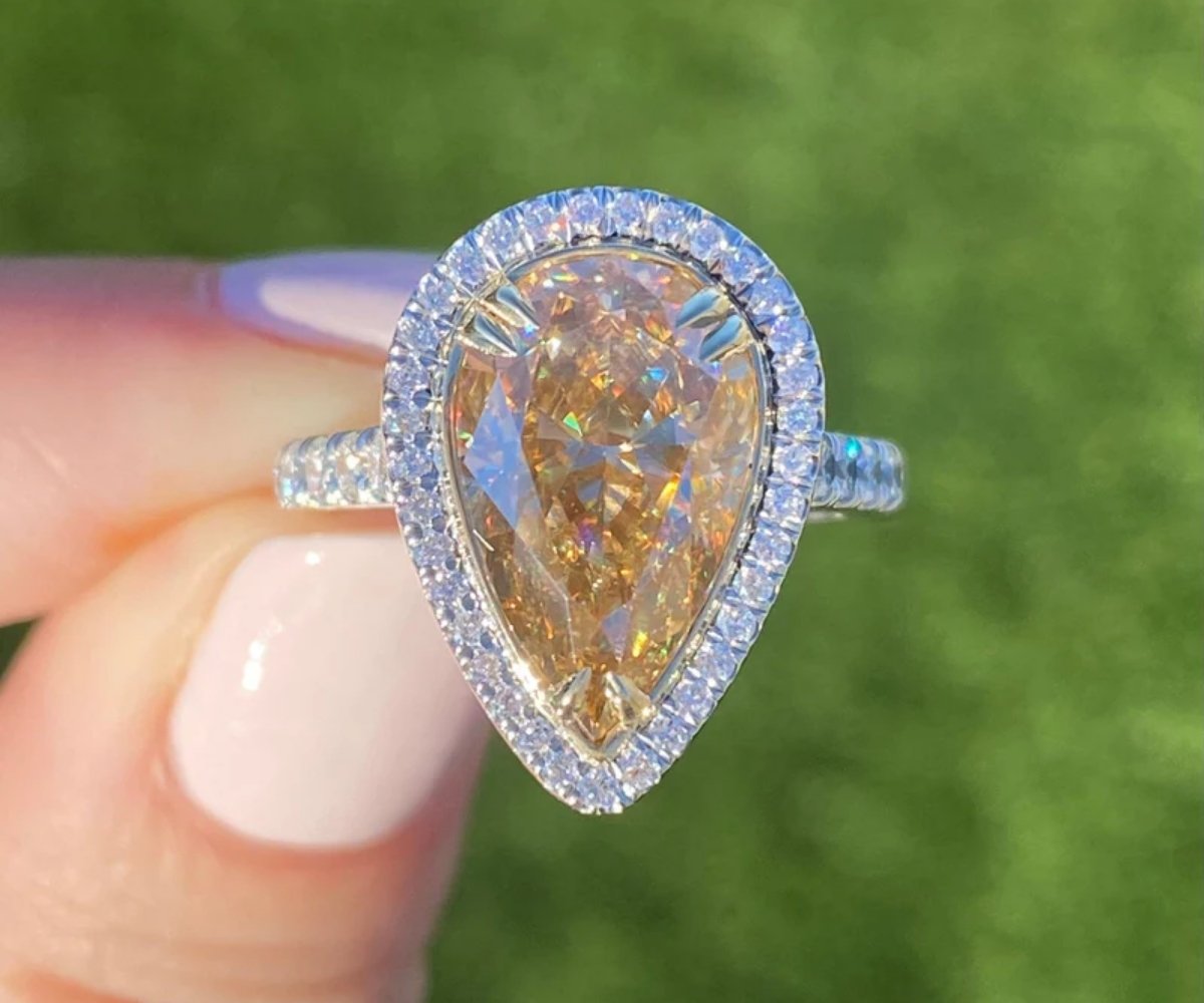 Pear-shaped halo engagement ring with a champagne diamond center stone and pavé diamond band.